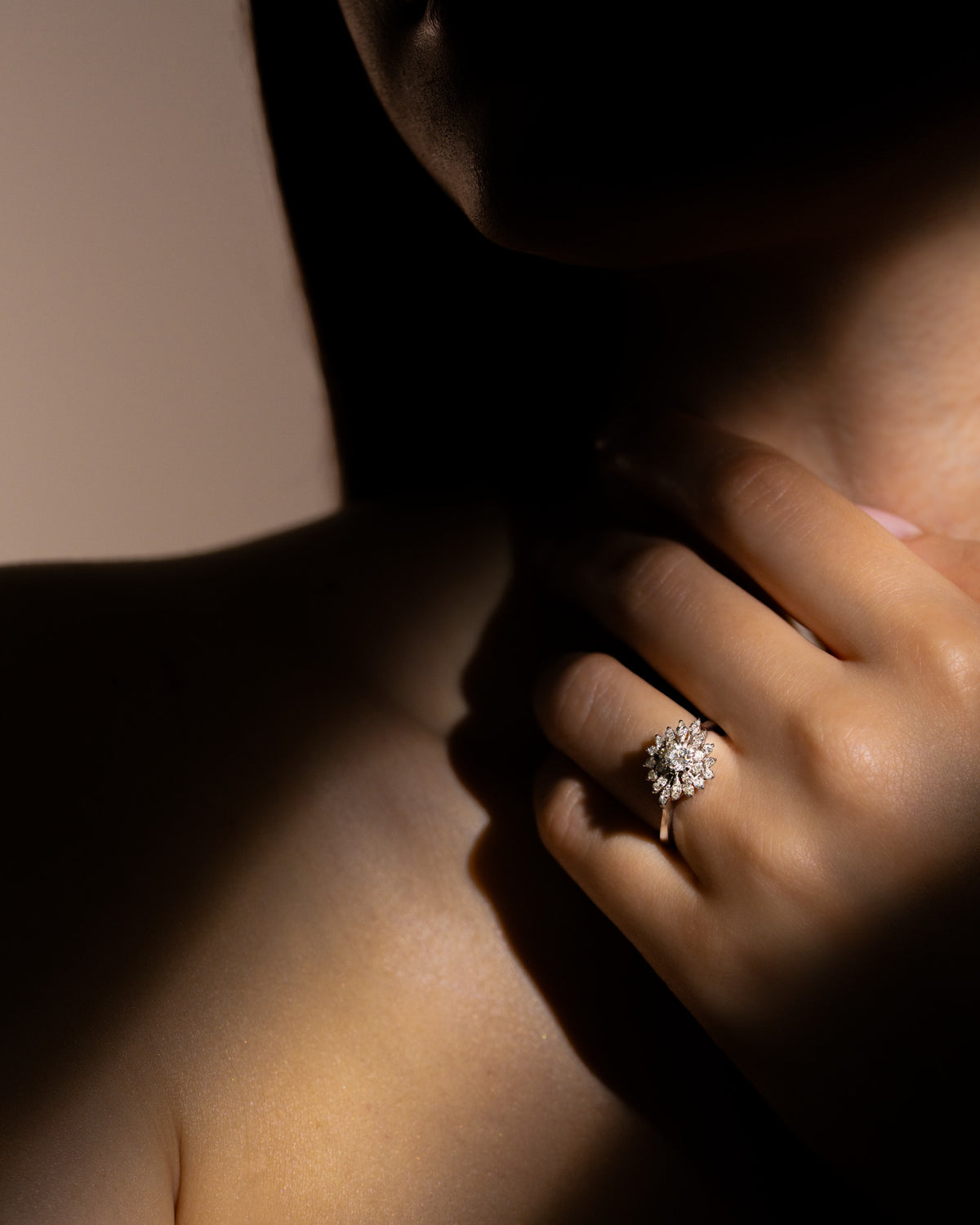 Anello Fiore Contemporaneo in oro bianco e diamanti indossato al dito, mano appoggiata sul collo