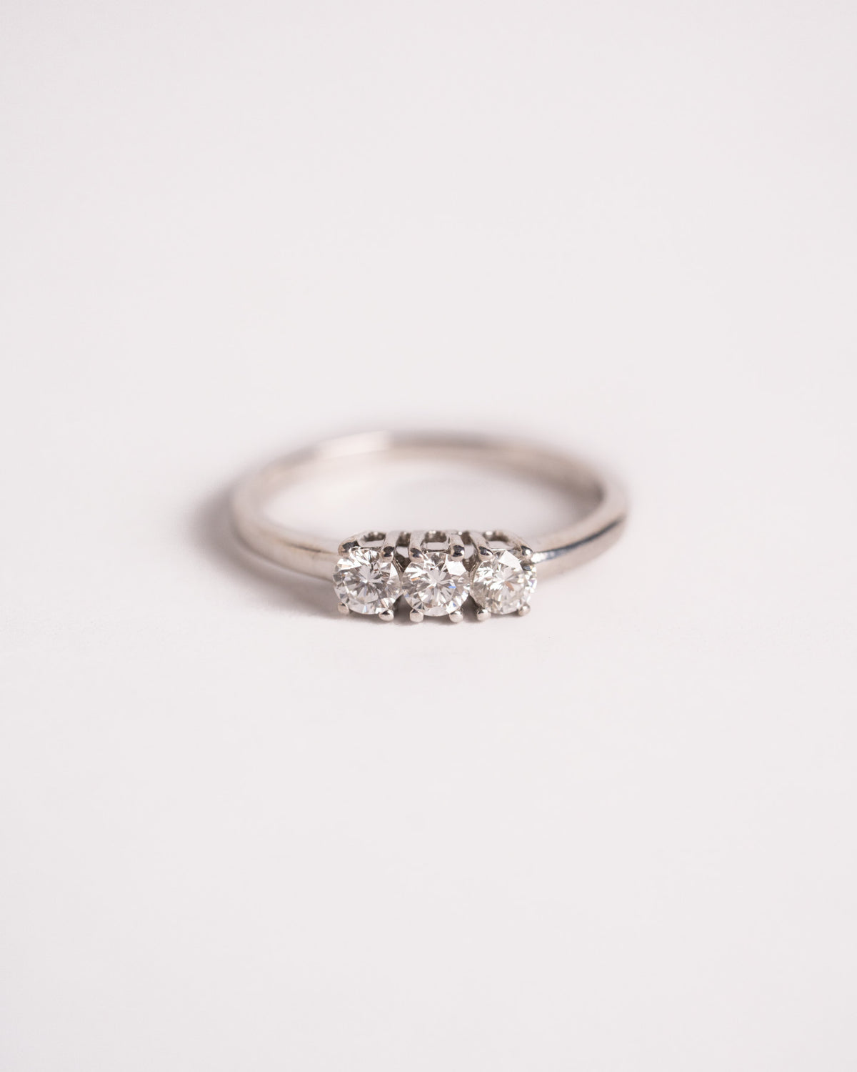 Anello trilogy con diamanti in oro bianco 18 carati, tre pietre tonde a griffe, still life su fondo chiaro, La Rosa
