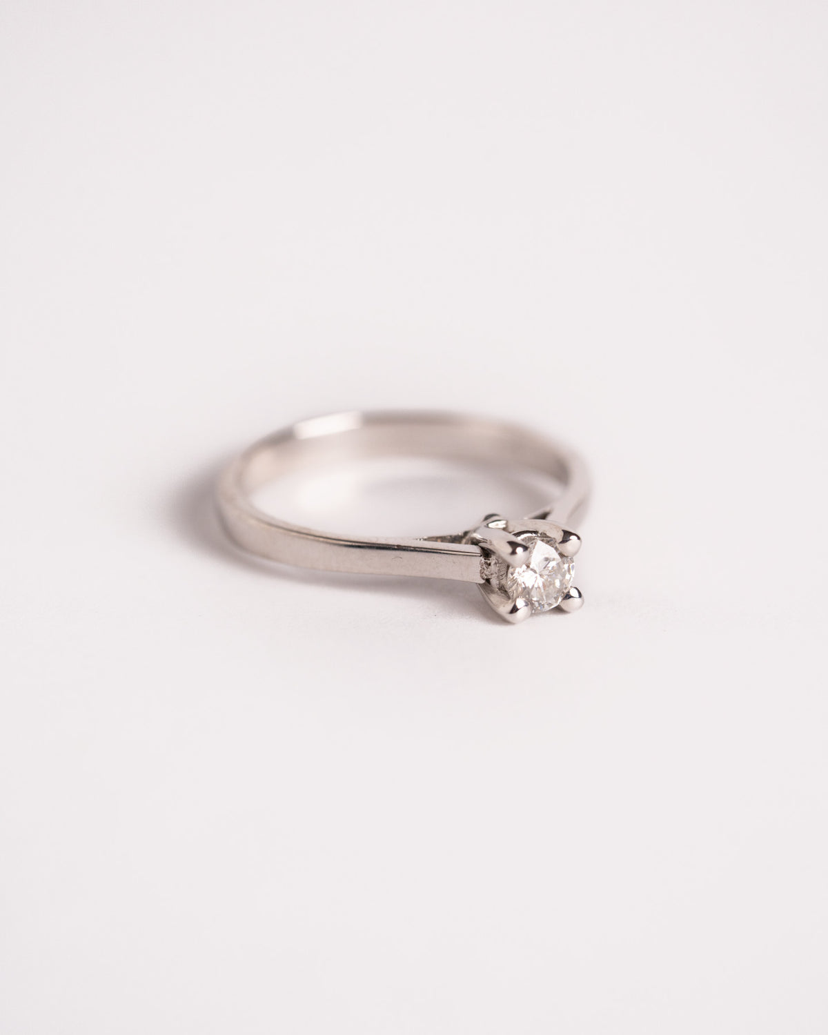 Anello solitario con diamante 0,20 ct in oro bianco 18 carati a 4 griffe, still life su fondo chiaro, Gioielleria La Rosa