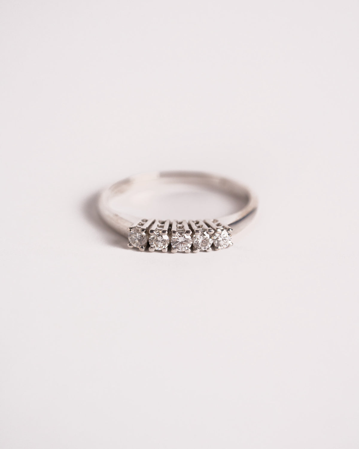 Anello veretta con 5 diamanti in oro bianco 18 carati su griffe alte, still life su fondo chiaro, Gioielleria La Rosa