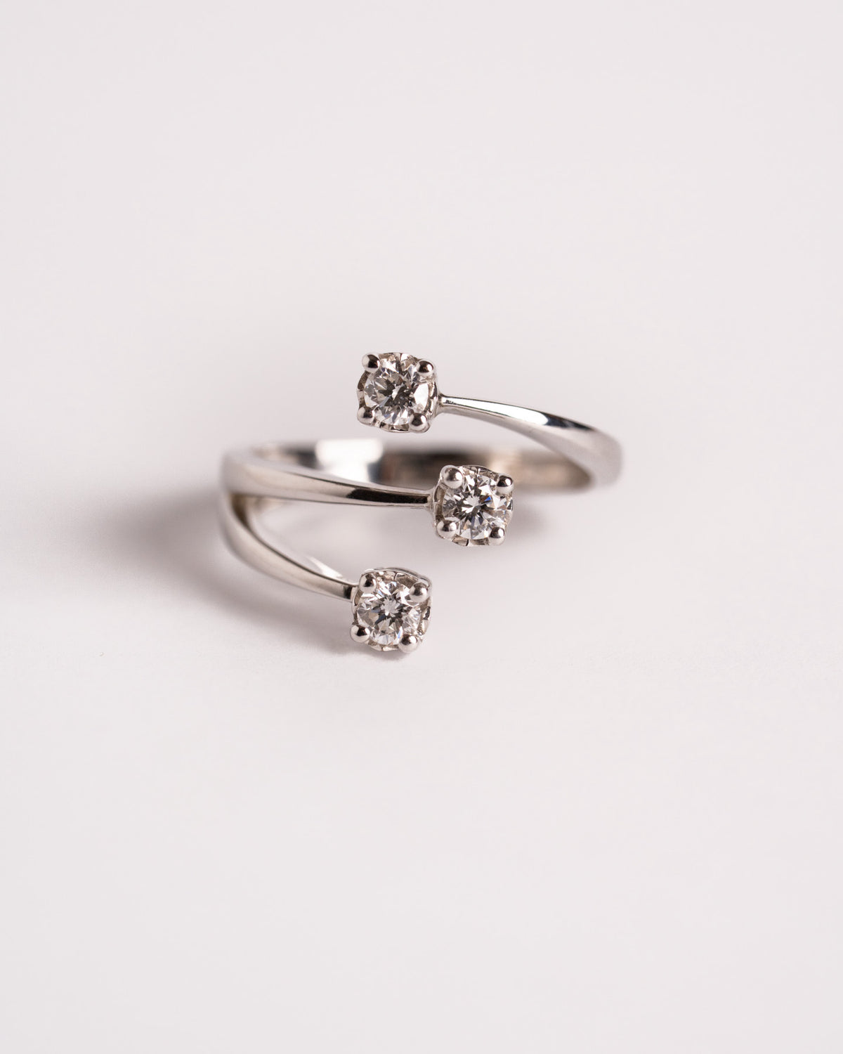 Anello contrarié in oro bianco con tre diamanti a griffe, still life su fondo chiaro, Gioielleria La Rosa