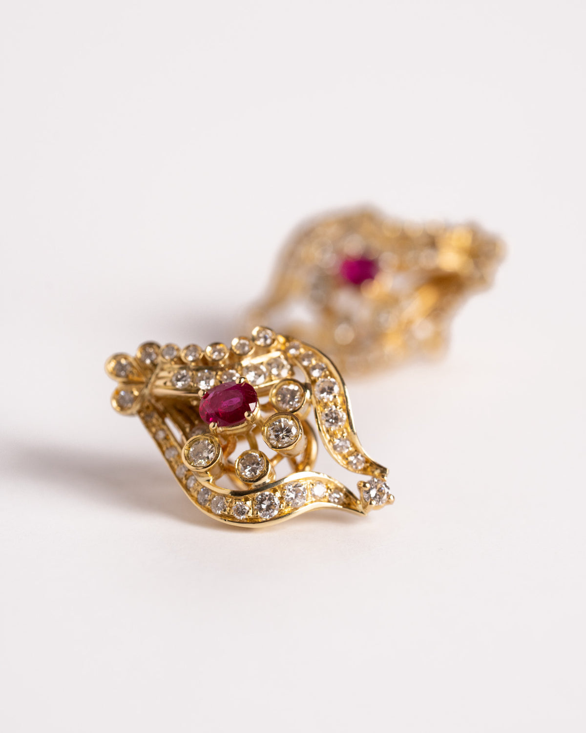 Orecchini con rubino e diamanti in oro giallo 18 carati, still life su fondo chiaro, Gioielleria La Rosa