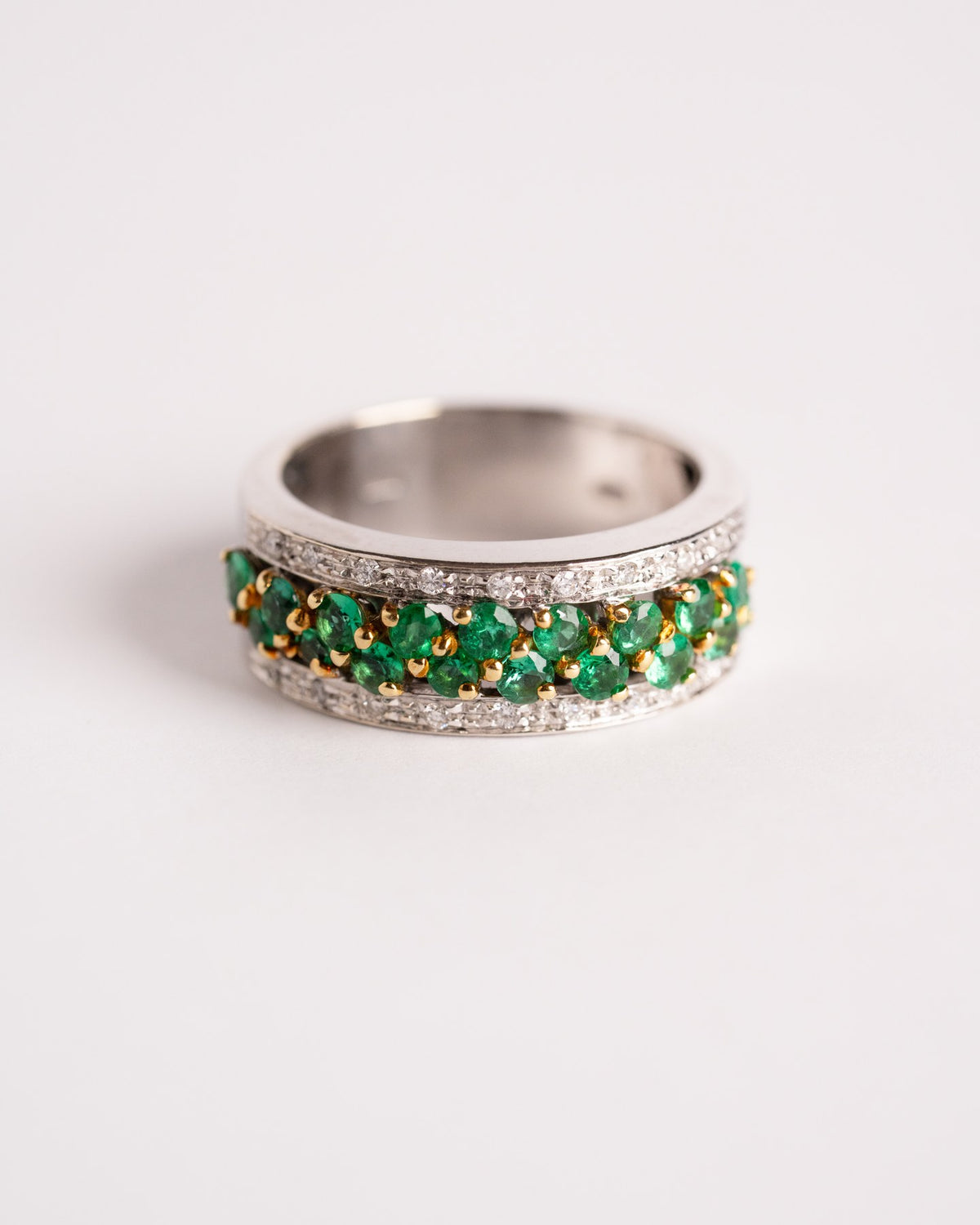 Anello a fascia con smeraldi e diamanti in oro bianco, still life su fondo chiaro, Gioielleria La Rosa