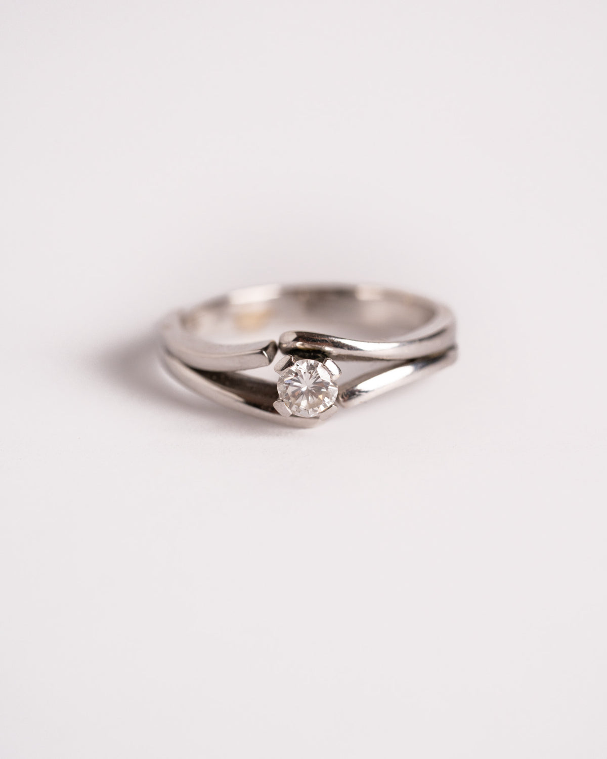 Solitario Abbraccio in oro bianco 18 carati con diamante 0,23 ct, still life su fondo chiaro, Gioielleria La Rosa