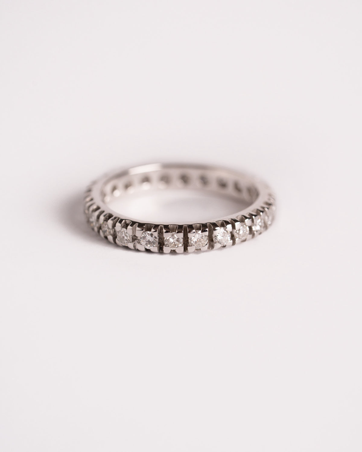 Anello eternity con diamanti in oro bianco, giro completo di pietre a griffe, still life su fondo chiaro, Gioielleria La Rosa