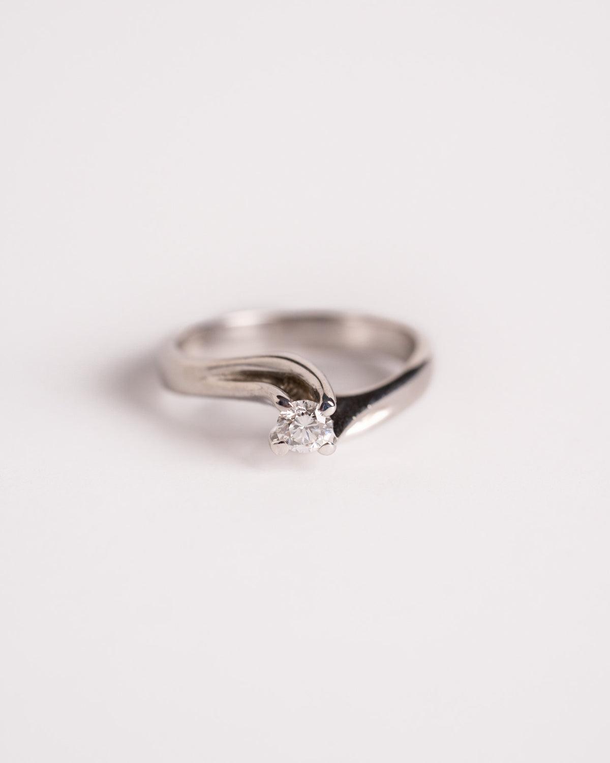 Anello solitario diamante oro bianco Nodo d’Amore con gambo avvolgente, still life su fondo chiaro, Gioielleria La Rosa
