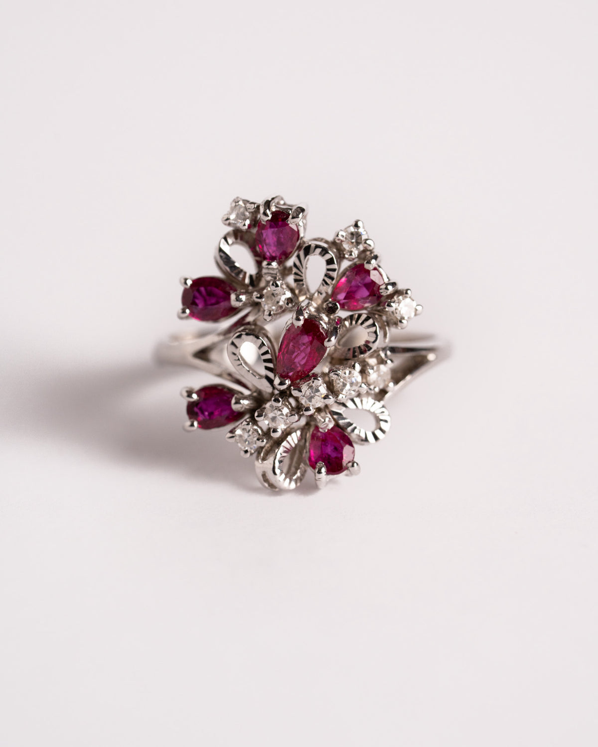 Anello a fiore con rubini e diamanti in oro bianco 18 carati, still life su fondo chiaro, Gioielleria La Rosa