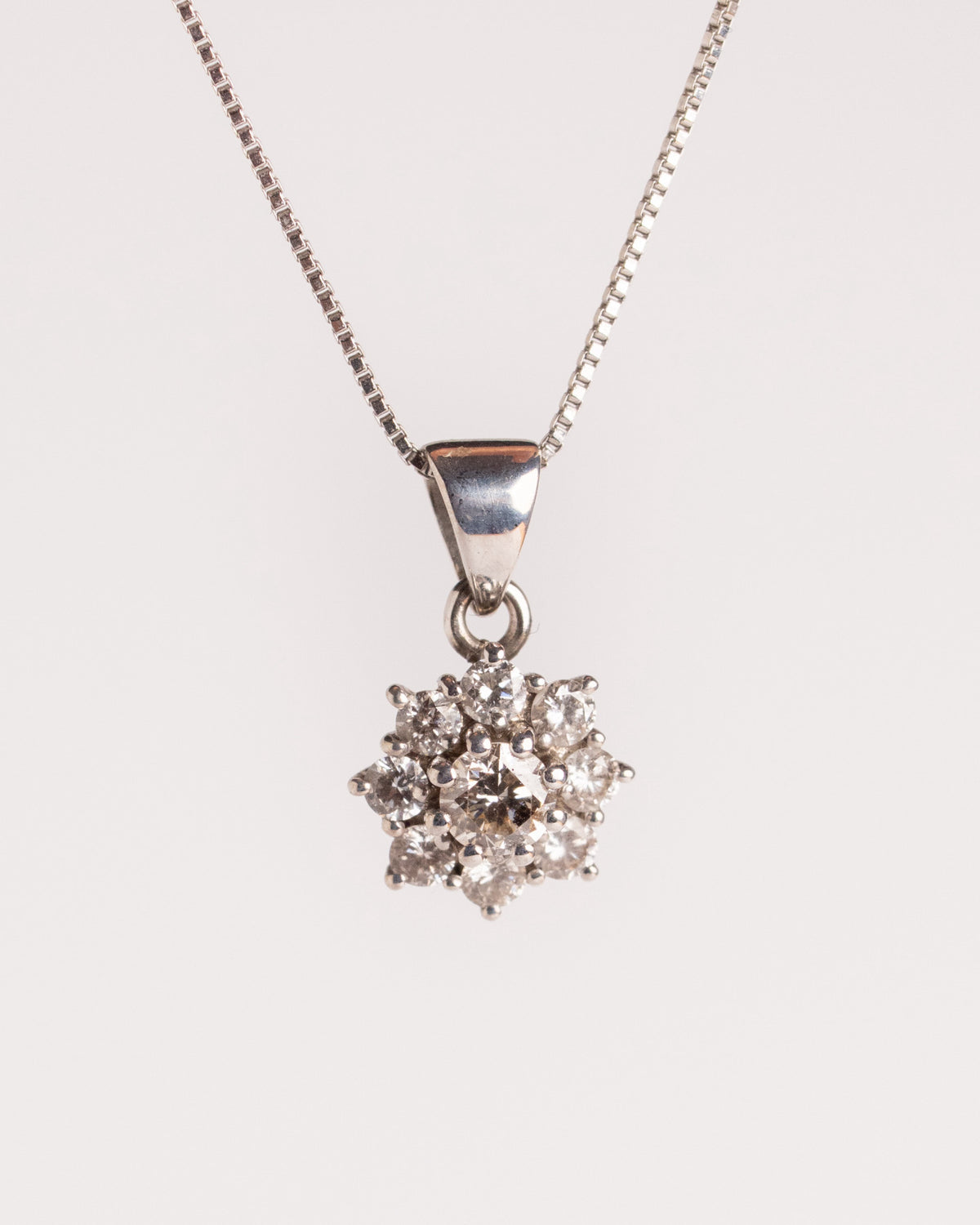 Collana con pavé di diamanti in oro bianco, pendente a fiore su catena veneziana, still life su fondo chiaro, La Rosa